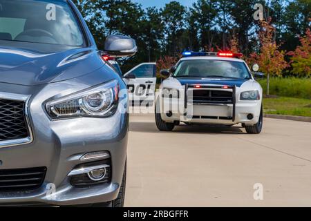 Deux véhicules de police arrêtent une berline lors d'un arrêt de circulation de routine Banque D'Images