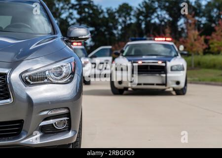 Deux véhicules de police arrêtent une berline lors d'un arrêt de circulation de routine Banque D'Images