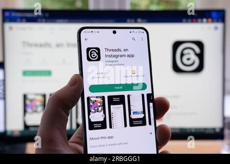 Main d'homme tenant un smartphone affichant l'écran de téléchargement et d'installation de Google Play pour les fils et son logo, une application Instagram de Meta. ROYAUME-UNI Banque D'Images