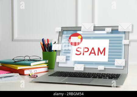 Message d'avertissement de spam dans le logiciel de messagerie. Illustrations d'enveloppes sortant de l'écran de l'ordinateur portable sur le bureau Banque D'Images