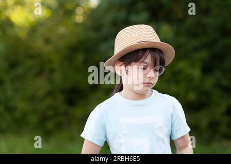 Mignonne petite fille portant un chapeau de paille et des lunettes dans le parc Banque D'Images