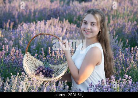 fille positive dans le champ de fleurs de lavande. adolescente tenant un bouquet de fleurs de lavande. Portrait d'une belle jeune fille aux cheveux longs dans un Banque D'Images