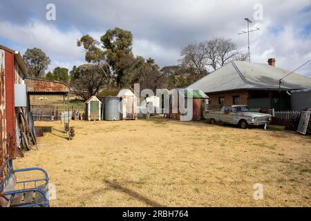 Juillet 2023, centre-ville du village de Sofala et propriété résidentielle avec voiture vintage rouillée garée sur la zone d'herbe sèche brune, Nouvelle-Galles du Sud, Australie Banque D'Images