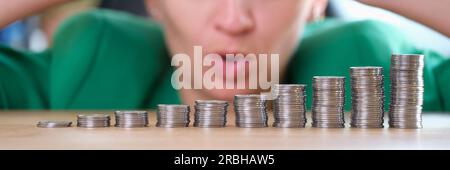 Femme choquée regardant des piles de pièces de monnaie et tenant sur la tête Banque D'Images