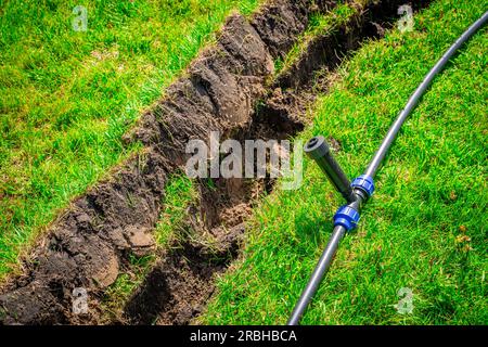 Auto-installation de l'irrigation avec un arroseur rétractable dans la pelouse finie. Pose de conduites d'eau avec des pulvérisateurs sous la pelouse pour l'irrigation. Banque D'Images