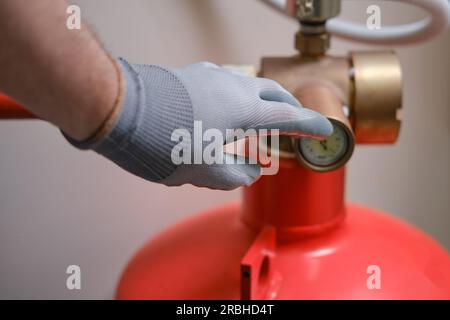 L'inspecteur de la sécurité incendie effectue une vérification de tous les extincteurs à l'intérieur du bâtiment pour s'assurer qu'ils sont en bon état de fonctionnement. Banque D'Images