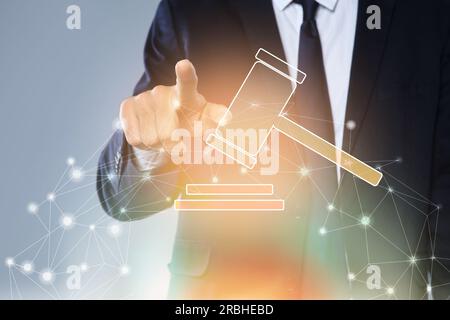 Vente aux enchères. Homme touchant l'écran numérique avec illustration du marteau et bloc sonore sur fond gris, gros plan Banque D'Images