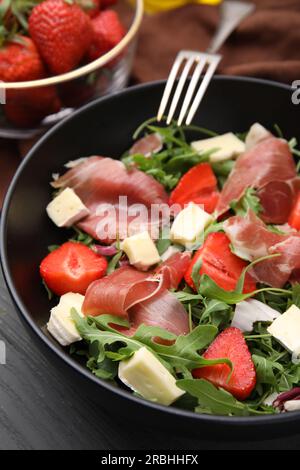 Salade savoureuse avec du brie, du prosciutto et des fraises sur table, gros plan Banque D'Images