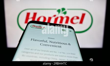 Téléphone portable avec le site Web de la société alimentaire américaine Hormel Foods Corporation sur l'écran devant le logo de l'entreprise. Effectuez le focus sur le coin supérieur gauche de l'écran du téléphone. Banque D'Images