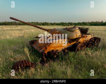 Détruit rouillé, abandonné et brûlé le char de combat dans les champs verts au coucher du soleil. Vous pouvez utiliser cette image comme illustration par exemple guerre Banque D'Images