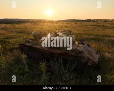 Détruit rouillé, abandonné et brûlé le char de combat dans les champs verts au coucher du soleil. Vous pouvez utiliser cette image comme illustration par exemple guerre Banque D'Images