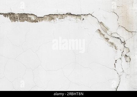 Vieux mur de ciment blanc avec des fissures complexes et des motifs uniques. La texture rugueuse et l'arrière-plan vieilli avec espace de copie. Banque D'Images