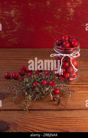 Traitements renforçant l'immunité. Thym naturel, herbes de menthe et baies de rose musquée dans un bocal sur un fond en bois. Remèdes phyto-thérapeutiques, infusi de soins de santé Banque D'Images