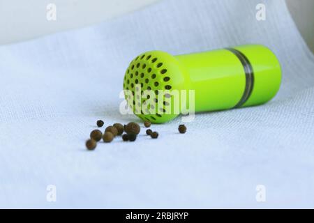 Grains de poivre noir et allspice dans le mortier en métal ancien avec pilon sur fond de lin. Vieux appareils ménagers de cuisine pour broyer des épices, des noix, des herbes, Banque D'Images