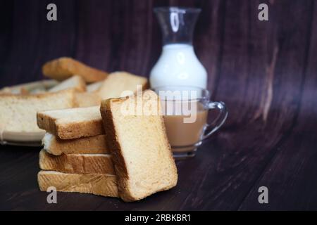 En-cas Tea Time. Rush de blé sain servi avec thé chaud indien masala et pichet à lait sur fond noir. Aussi connu sous le nom de Mumbai Cutting chai. Banque D'Images