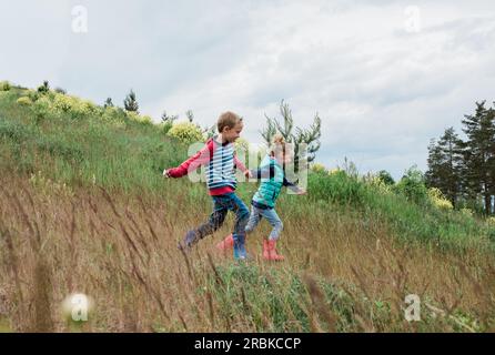 fille et garçon courant sur une colline en se tenant la main Banque D'Images