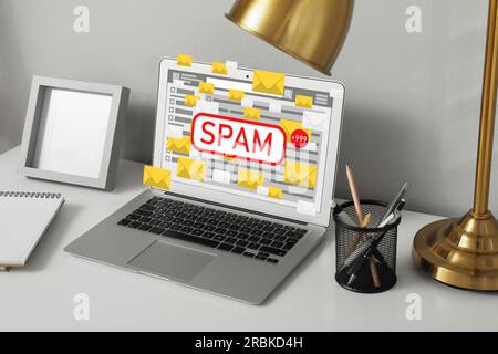 Message d'avertissement de spam dans le logiciel de messagerie. Illustrations d'enveloppes sortant de l'écran de l'ordinateur portable sur le bureau Banque D'Images