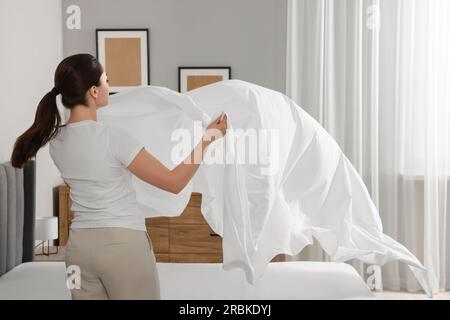 Jeune femme changeant le linge de lit à la maison Banque D'Images