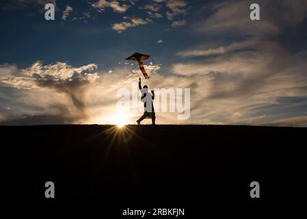 Silhouette d'une fille de 9 ans volant un cerf-volant Banque D'Images