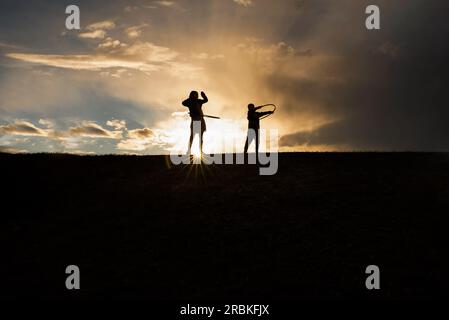 Silhouette de frères et sœurs hoola Hooping Banque D'Images