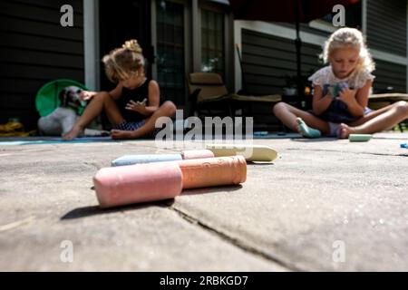 filles dessinant à la craie sur le patio extérieur en été Banque D'Images