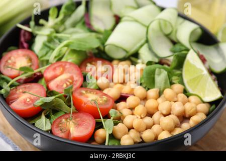 Salade savoureuse avec des pois chiches, des tomates cerises et des concombres dans un bol, gros plan Banque D'Images