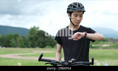 Homme de sport biker utilisant GPS activité tracker montre de fitness à l'entraînement dans le parc homme de sport utilisant montre application de suivi de fitness. Banque D'Images