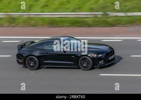 2016 Black Ford Mustang GT Auto ; voyageant à grande vitesse sur l'autoroute M6 dans le Grand Manchester, Royaume-Uni Banque D'Images