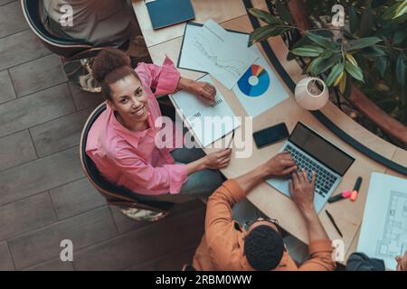 Vue de dessus des collègues d'affaires travaillant avec des États financiers et utiliser un ordinateur portable dans le coworking moderne Banque D'Images
