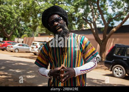 Heureux Rastafari personne portant des vêtements colorés et chapeau de laine, ayant des dreadlocks et une façon positive de penser, anneau de paix sur son doigt Banque D'Images