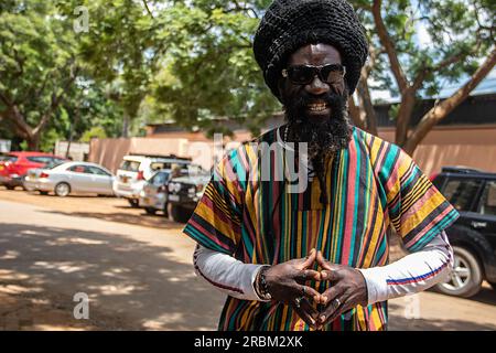 Heureux Rastafari personne portant des vêtements colorés et chapeau de laine, ayant des dreadlocks et une façon positive de penser, anneau de paix sur son doigt Banque D'Images