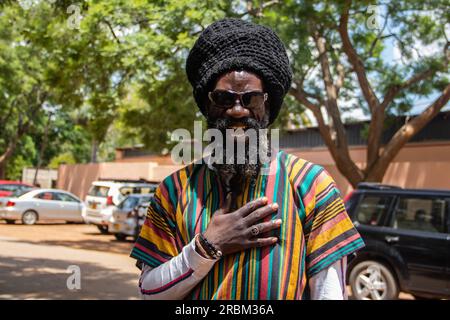 Heureux Rastafari personne portant des vêtements colorés et chapeau de laine, ayant des dreadlocks et une façon positive de penser, anneau de paix sur son doigt Banque D'Images