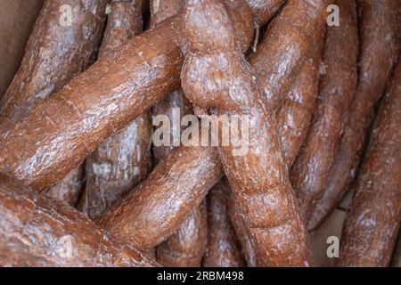 Une photo en gros plan d'un tas de manioc brut exposé dans un magasin de détail, mettant en valeur leur forme et leur texture naturelles. Banque D'Images