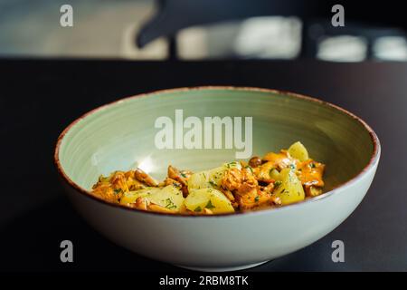 Déjeuner d'été frais à base de produits végétariens locaux. Chanterelles sauvages avec pommes de terre bouillies et herbes dans un bol sur la table. Banque D'Images