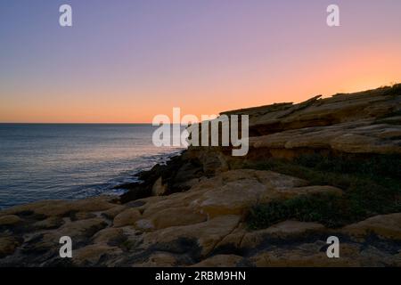 Coucher de soleil sur la côte rocheuse sur l'Atlantique entre Burgau et Luz à l'ouest de Lagos, Algarve, Barlavento, Algarve occidental, Algarve rocheux, District de Faro, Banque D'Images