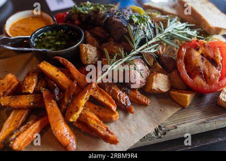 Une merveilleuse planche avec des frites de patates douces, des herbes et de la viande vous attend! Banque D'Images