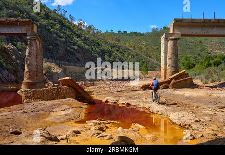 Belle femme avec vélo de montagne électrique sur un tour à vélo le long de la rivière Rio Tinto avec son eau rouge naturelle en Andalousie, Espagne Banque D'Images