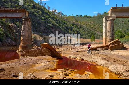 Belle femme avec vélo de montagne électrique sur un tour à vélo le long de la rivière Rio Tinto avec son eau rouge naturelle en Andalousie, Espagne Banque D'Images