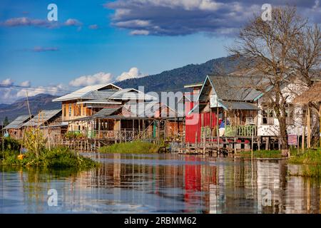 Maisons colorées sur pilotis le long de la voie navigable à travers la ville de Nang Pang dans le lac Inle peu profond au Myanmar, en Asie Banque D'Images