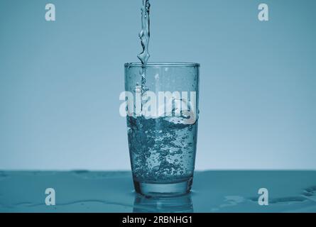 de l'eau fraîche est versée dans le verre. Banque D'Images