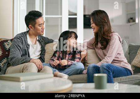 jeune mère asiatique et père assis sur le canapé de la famille à la maison ayant une conversation agréable avec sa fille Banque D'Images