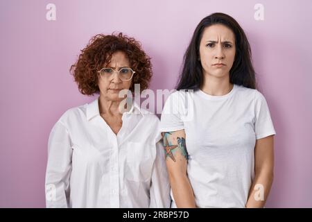 Mère hispanique et fille portant un t-shirt blanc décontracté sur fond rose sceptique et nerveux, frowning bouleversé à cause du problème. personne négative Banque D'Images