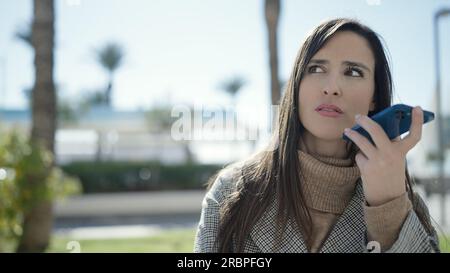 Belle femme hispanique envoyant un message vocal avec un smartphone dans la rue Banque D'Images