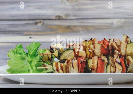 Savourez des brochettes de tofu et de légumes, glacées avec de la sauce soja, sur un plateau en céramique Un délicieux délice végétarien, parfait pour toute occasion Banque D'Images