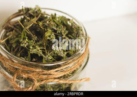 Thym séché dans un bocal en verre sur fond en bois. Tisane en pot. Concept de produits ECO. Nourriture saine. Tisane maison. Séchez le thym avec des fleurs. Banque D'Images