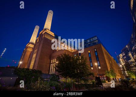 Battersea, Londres, Royaume-Uni : Battersea Power Station est maintenant réaménagé pour devenir une destination de shopping et de loisirs. Vue nocturne avec fleurs au premier plan. Banque D'Images