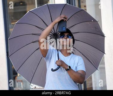 Rome, Italie. 10 juillet 2023. Un homme se réfugie du soleil sous un parapluie à Rome, Italie, le 10 juillet 2023. Rome et d'autres villes à travers l'Italie ont été mises en alerte rouge lundi alors que le pays se préparait à une vague de chaleur intense qui, selon les météorologues, était susceptible de battre des records. Crédit : Jin Mamengni/Xinhua/Alamy Live News Banque D'Images