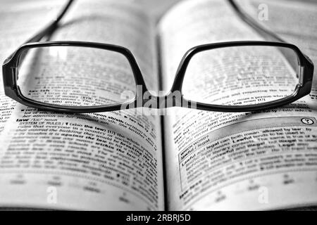 Lunettes noires allongées sur un dictionnaire Banque D'Images