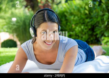 Femme avec des écouteurs dans le parc public sur la couverture Banque D'Images