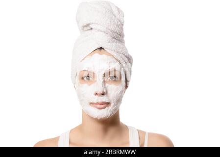 Femme sérieuse avec ses cheveux attachés dans une serviette blanche et un masque facial nourrissant nettoyant en profondeur appliqué sur elle, beauté et concept de soins de la peau Banque D'Images